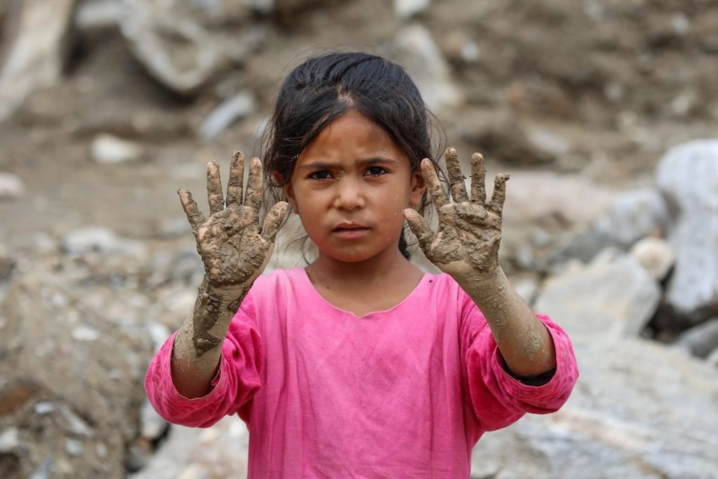 Una niña afgana junto a su casa destruida por las inundaciones. EFE