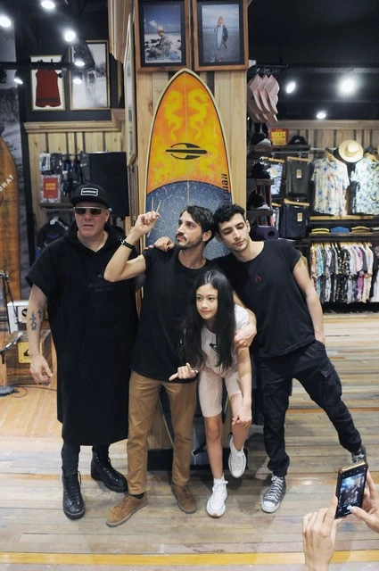 Los Catupecu y Lila, la hija de Fernando, posando junto a la tabla y las fotos de Gaby, el bajista de la banda fallecido en enero.