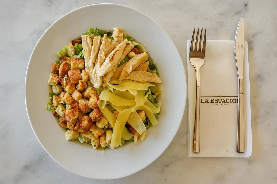 Lechugas frescas, pechuga grillada, crotones dorados, láminas de parmesano y el aderezo justo