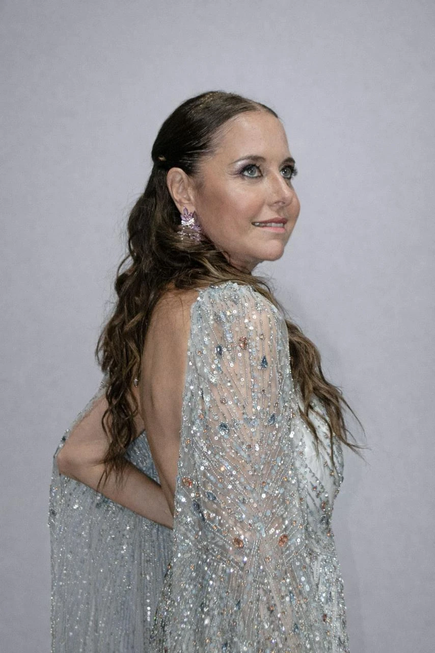 El trabajo artesanal en cristales y pedrería crea un delicado juego de luz, mientras la capa transparente aporta movimiento y elegancia.